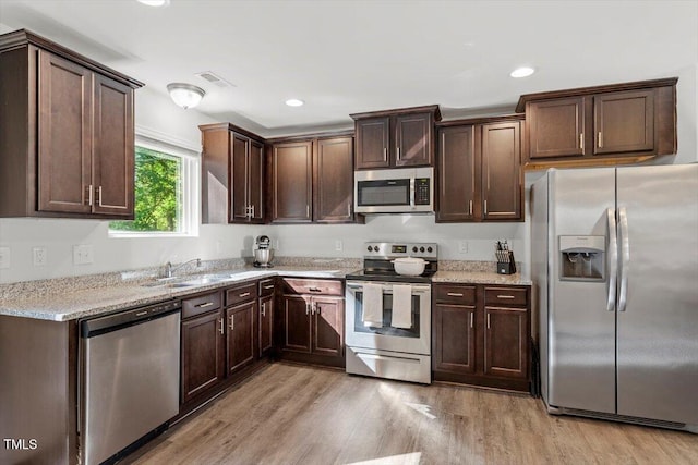534 Hobkirks Pl, Durham, NC 27704 - kitchen featuring appliances with stainless steel finishes, light wood-type flooring, dark brown cabinetry, light stone counters, and recessed lighting