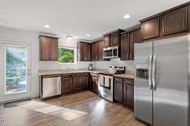 534 Hobkirks Pl, Durham, NC 27704 - kitchen featuring stainless steel appliances, dark brown cabinetry, light stone countertops, light wood-style flooring, and recessed lighting