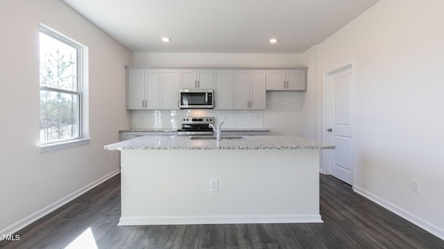 170 Babbling Creek Dr, Youngsville, NC 27596 - kitchen featuring stainless steel appliances, tasteful backsplash, a center island with sink, dark wood-style flooring, and light stone counters