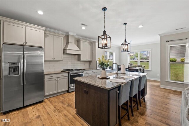 824 Stanly House St, Wake Forest, NC 27587 - kitchen featuring appliances with stainless steel finishes, premium range hood, ornamental molding, a breakfast bar area, and light stone countertops