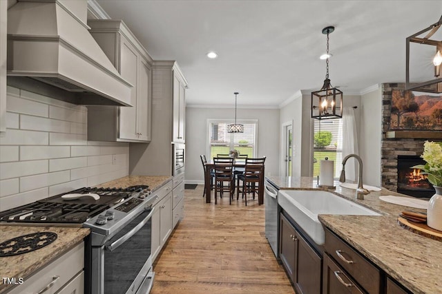 824 Stanly House St, Wake Forest, NC 27587 - kitchen with stainless steel appliances, custom range hood, ornamental molding, light wood-style flooring, and backsplash
