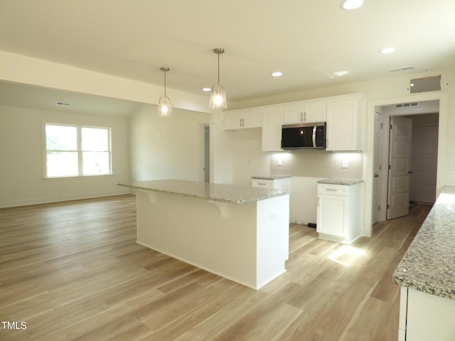 5610 Plain View Highway, Dunn, NC 28334 - kitchen with stainless steel microwave, white cabinets, recessed lighting, light stone countertops, and light wood-style flooring