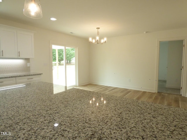 5610 Plain View Highway, Dunn, NC 28334 - kitchen featuring a chandelier, white cabinetry, light wood-style floors, decorative backsplash, and light stone countertops
