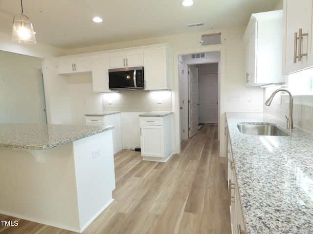 5610 Plain View Highway, Dunn, NC 28334 - kitchen featuring stainless steel microwave, light stone countertops, white cabinets, decorative backsplash, and recessed lighting
