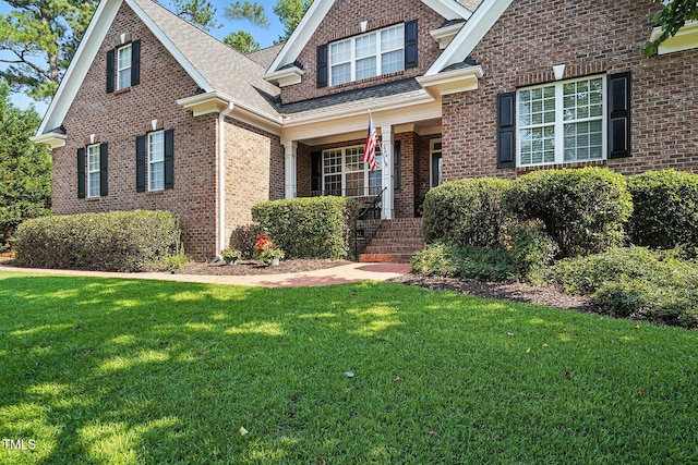 164 Avocet Ln, Clayton, NC 27520 - traditional-style house with a front lawn, brick siding, a porch, and a shingled roof