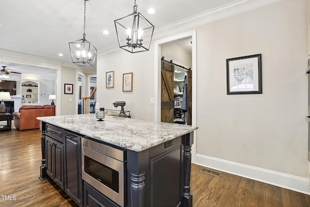 164 Avocet Ln, Clayton, NC 27520 - kitchen featuring stainless steel microwave, a barn door, ornamental molding, a ceiling fan, and dark wood-type flooring