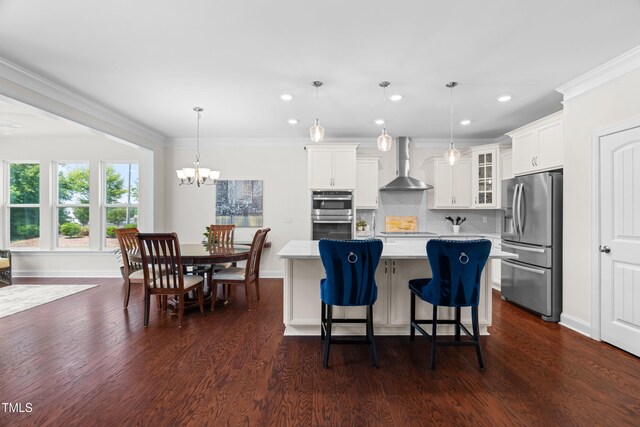 1321 White Spruce Dr, Willow Springs, NC 27592 - kitchen with stainless steel appliances, wall chimney range hood, light countertops, a kitchen island, and glass insert cabinets