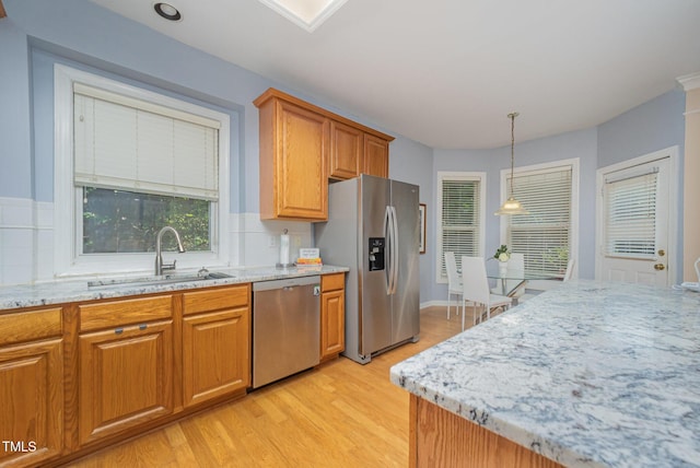 302 Caraway Ln, Cary, NC 27519 - kitchen with stainless steel appliances, light stone counters, light wood-style floors, tasteful backsplash, and brown cabinetry