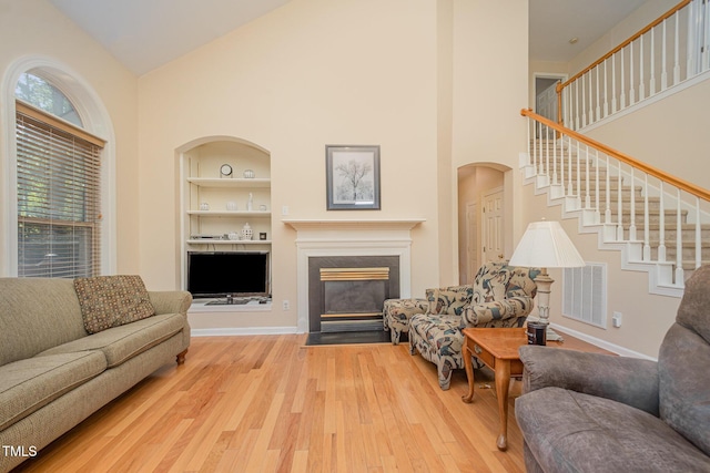302 Caraway Ln, Cary, NC 27519 - living area with built in shelves, high vaulted ceiling, wood finished floors, stairway, and a fireplace with flush hearth