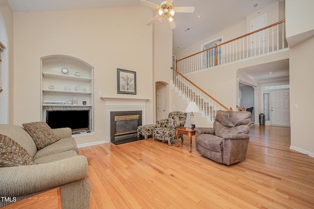 302 Caraway Ln, Cary, NC 27519 - living area featuring stairway, wood finished floors, built in features, a towering ceiling, and a fireplace with flush hearth