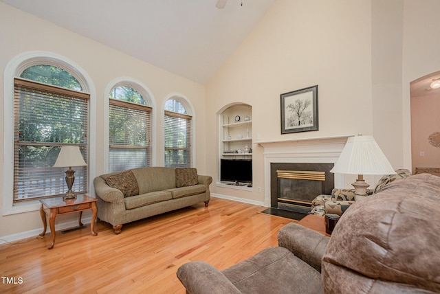 302 Caraway Ln, Cary, NC 27519 - living room featuring built in shelves, high vaulted ceiling, healthy amount of natural light, wood finished floors, and a fireplace