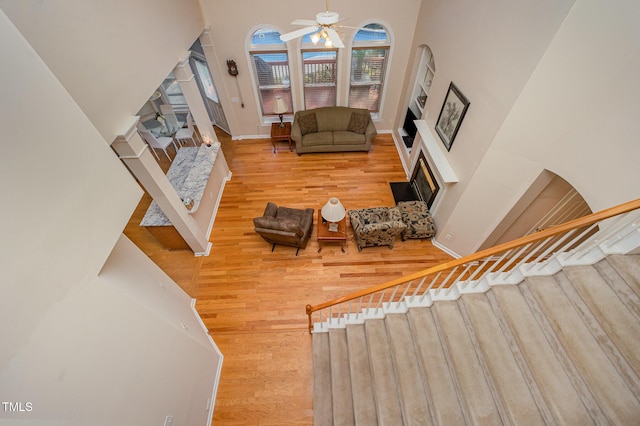 302 Caraway Ln, Cary, NC 27519 - living room featuring a towering ceiling, a fireplace with flush hearth, a ceiling fan, wood finished floors, and stairs