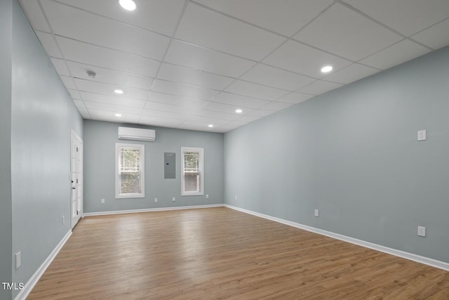 145 Mariah Towns Way, Garner, NC 27529 - unfurnished room featuring an AC wall unit, electric panel, wood finished floors, a smoke detector, and a paneled ceiling