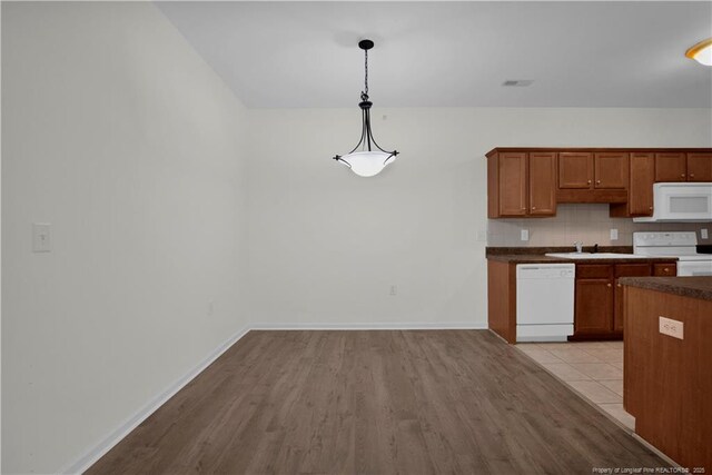612 Marshtree Ln Unit 304, Fayetteville, NC 28314 - kitchen featuring white appliances, decorative backsplash, light wood finished floors, and brown cabinetry
