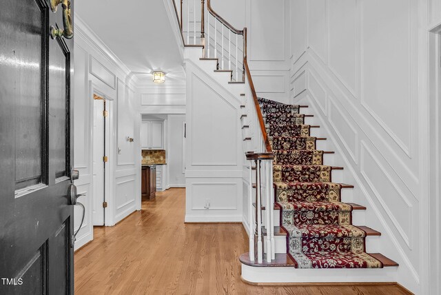 105 Bathgate Ln, Cary, NC 27513 - foyer entrance with a decorative wall, stairway, light wood-style floors, and ornamental molding