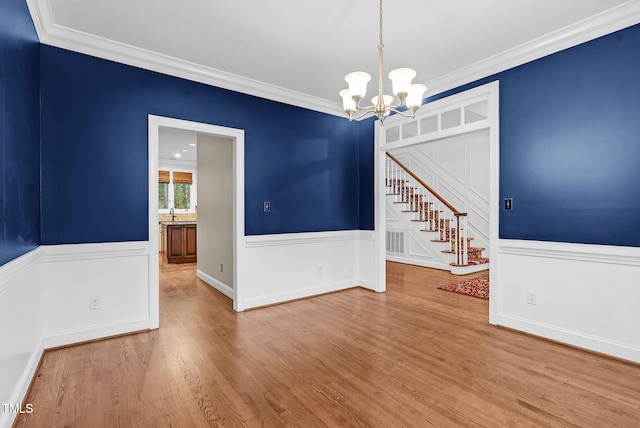 105 Bathgate Ln, Cary, NC 27513 - unfurnished room featuring a chandelier, stairs, wainscoting, crown molding, and wood finished floors