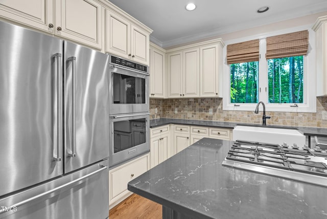 105 Bathgate Ln, Cary, NC 27513 - kitchen with appliances with stainless steel finishes, decorative backsplash, crown molding, dark stone countertops, and light wood-type flooring