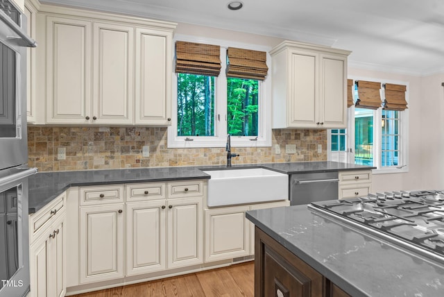 105 Bathgate Ln, Cary, NC 27513 - kitchen featuring stainless steel appliances, backsplash, crown molding, dark stone counters, and light wood-style flooring