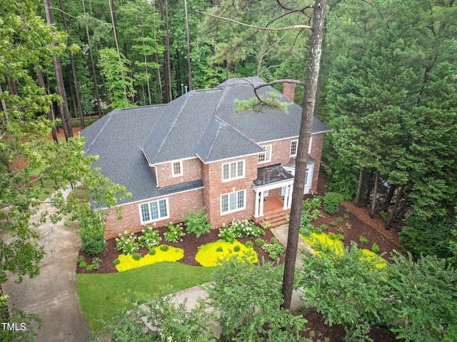 105 Bathgate Ln, Cary, NC 27513 - view of front of house featuring a chimney, brick siding, roof with shingles, and a wooded view