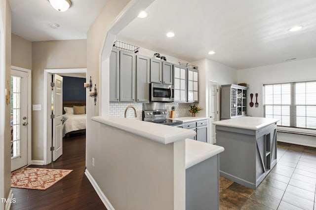 8205 Rolling Glenn Dr, Raleigh, NC 27616 - kitchen featuring appliances with stainless steel finishes, gray cabinetry, decorative backsplash, a kitchen island, and light countertops
