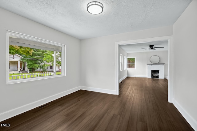 208 Fairview Ave SW, Wilson, NC 27893 - unfurnished living room featuring dark wood-style floors, ceiling fan, a textured ceiling, and a fireplace