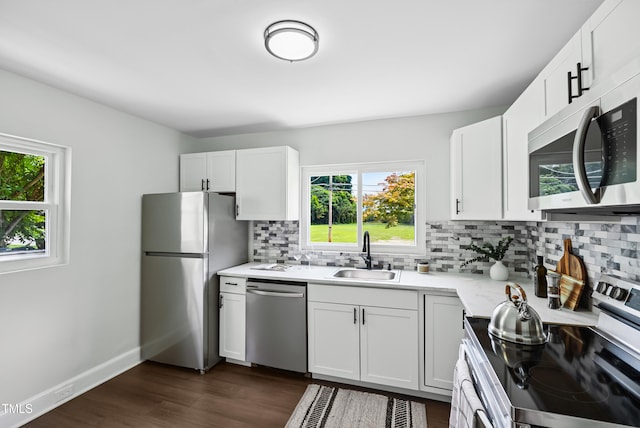 208 Fairview Ave SW, Wilson, NC 27893 - kitchen with appliances with stainless steel finishes, backsplash, light countertops, dark wood-type flooring, and white cabinetry