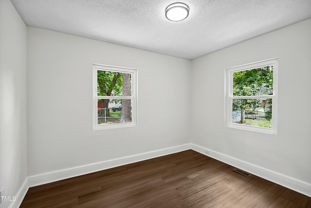 208 Fairview Ave SW, Wilson, NC 27893 - empty room featuring plenty of natural light, dark wood-type flooring, and a textured ceiling
