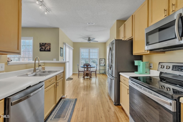1968 Shadow Glen Dr, Raleigh, NC 27604 - kitchen featuring stainless steel appliances, light brown cabinetry, light countertops, a textured ceiling, and light wood-style floors