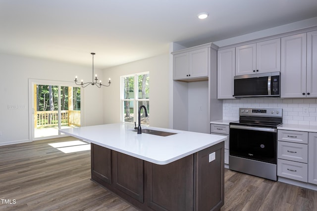 6069 Jones Cir, Sanford, NC 27332 - kitchen featuring appliances with stainless steel finishes, dark wood-type flooring, a chandelier, light countertops, and tasteful backsplash