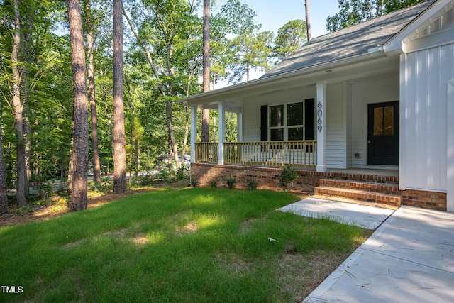 6069 Jones Cir, Sanford, NC 27332 - view of exterior entry featuring board and batten siding, covered porch, a lawn, and a shingled roof