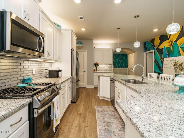67 Blue Spruce Cir, Clayton, NC 27527 - kitchen with stainless steel appliances, white cabinetry, tasteful backsplash, light wood-type flooring, and light stone counters