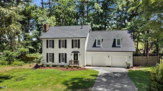 1609 Falls Ct, Raleigh, NC 27615 - colonial-style house featuring a chimney, driveway, roof with shingles, a garage, and view of wooded area