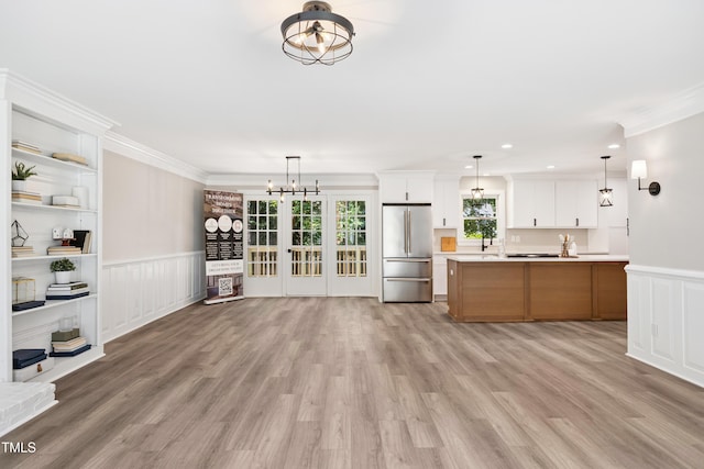 1609 Falls Ct, Raleigh, NC 27615 - unfurnished living room with a chandelier, ornamental molding, a wainscoted wall, light wood-type flooring, and a decorative wall