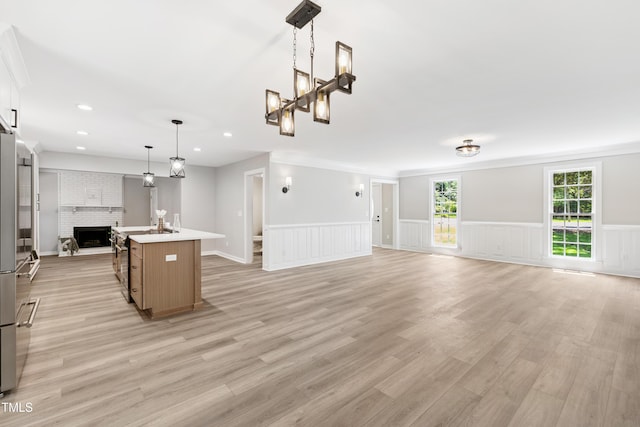 1609 Falls Ct, Raleigh, NC 27615 - unfurnished living room with a wainscoted wall, light wood-style flooring, recessed lighting, a fireplace, and a chandelier