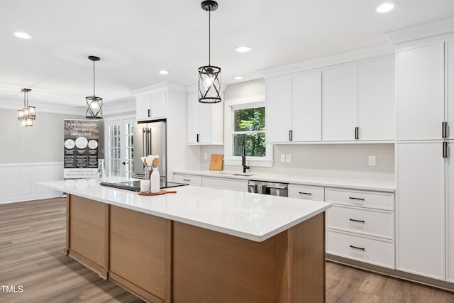 1609 Falls Ct, Raleigh, NC 27615 - kitchen featuring stainless steel appliances, white cabinets, light countertops, a wainscoted wall, and light wood-style flooring