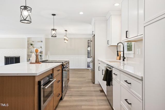 1609 Falls Ct, Raleigh, NC 27615 - kitchen featuring appliances with stainless steel finishes, a center island, white cabinets, wainscoting, and hanging light fixtures