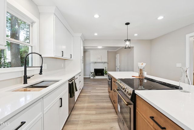 1609 Falls Ct, Raleigh, NC 27615 - kitchen with stainless steel appliances, light wood finished floors, a brick fireplace, recessed lighting, and light countertops