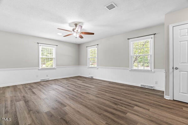 509 S Mckay Ave, Dunn, NC 28334 - unfurnished room with ceiling fan, plenty of natural light, wainscoting, and dark wood-style floors