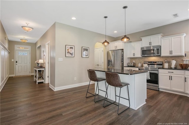 123 Sorrel Ct, Raeford, NC 28376 - kitchen featuring stainless steel appliances, arched walkways, dark countertops, a kitchen bar, and backsplash