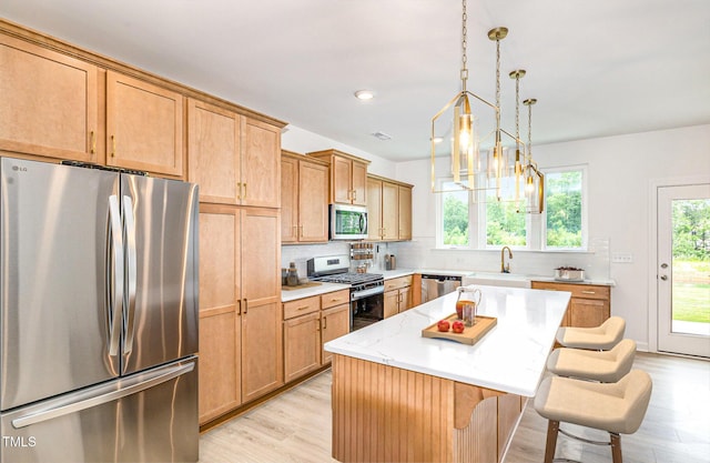 27 Silver Moon Ln, Clayton, NC 27527 - kitchen featuring appliances with stainless steel finishes, light wood finished floors, a breakfast bar area, backsplash, and a kitchen island