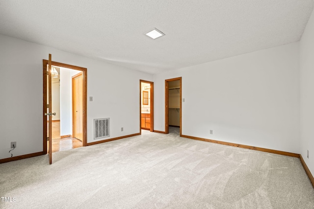 601 Wofford Rd, Durham, NC 27707 - unfurnished bedroom featuring light colored carpet, a walk in closet, and a textured ceiling