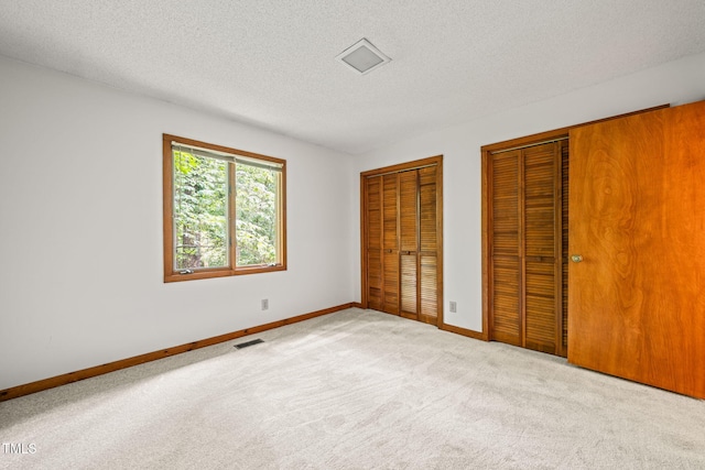 601 Wofford Rd, Durham, NC 27707 - unfurnished bedroom with two closets, carpet, and a textured ceiling