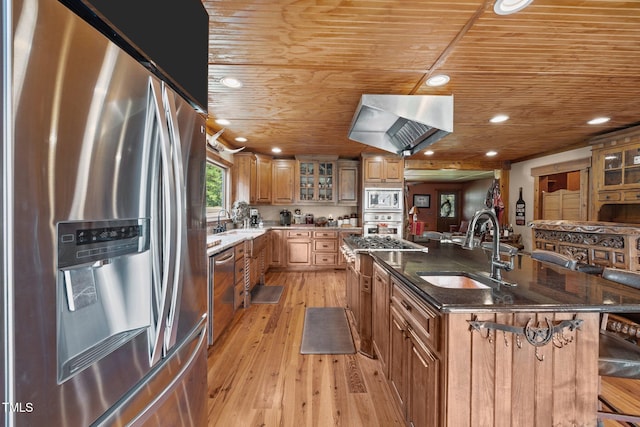 kitchen with appliances with stainless steel finishes, wooden ceiling, wall chimney range hood, a kitchen island with sink, and dark stone counters
