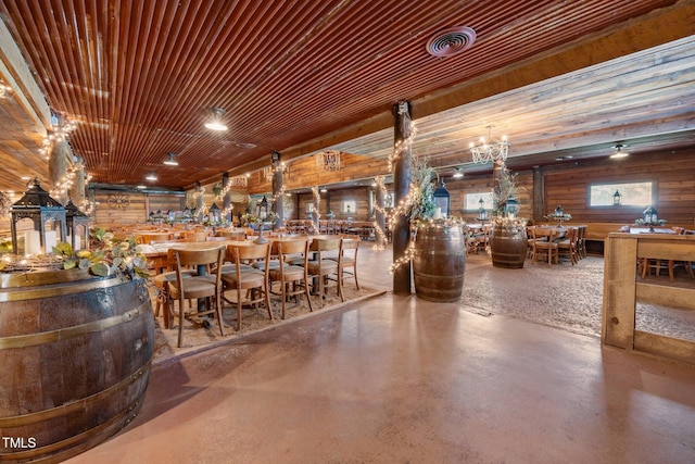 bar area with finished concrete floors, a chandelier, and wood walls