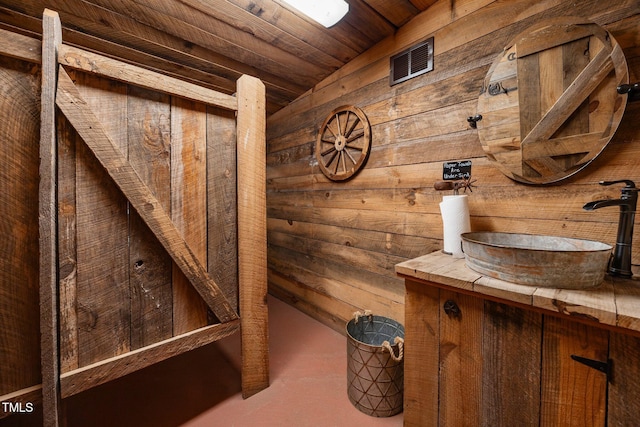 bathroom with wood walls, wood ceiling, and vanity