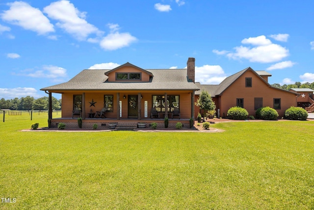back of house with a porch, a yard, a chimney, and a shingled roof