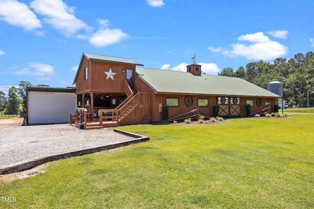 back of house featuring a yard, a metal roof, a chimney, an outdoor structure, and driveway
