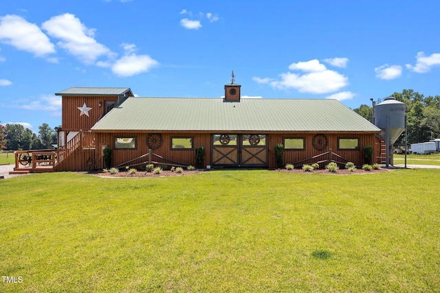 rear view of property featuring a lawn, a metal roof, a chimney, and an outdoor structure