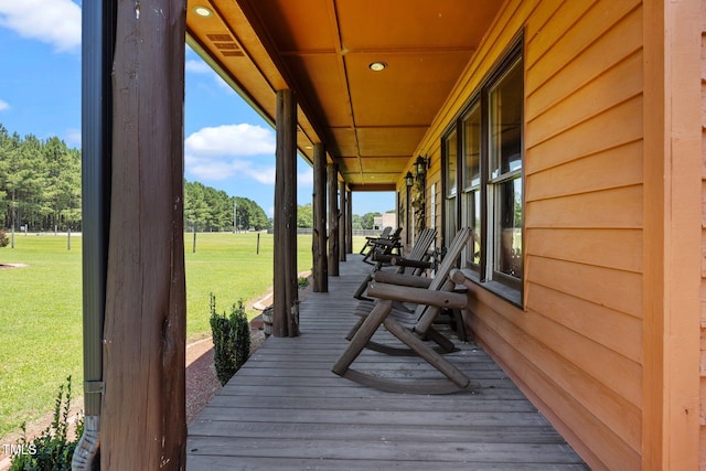 wooden porch featuring a lawn