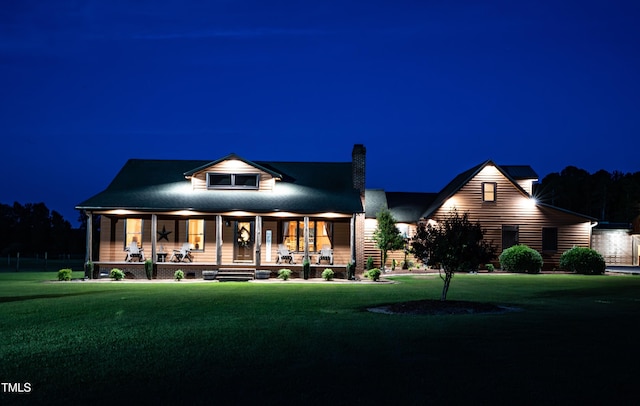 view of front of home featuring covered porch, a lawn, and a chimney